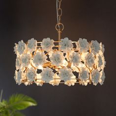 a chandelier with white flowers hanging from it's center and two lights on each side