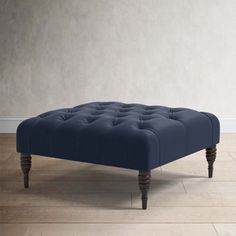 a blue ottoman sitting on top of a hard wood floor next to a white wall