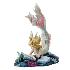 a statue of a mermaid reading a book