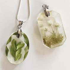 two necklaces with flowers and leaves on them sitting next to each other, one is green