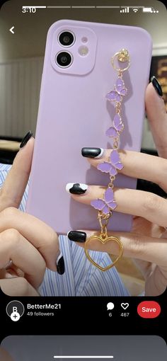 a person holding up a phone case with a chain attached to it and some rings hanging from the back