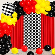 an arch made out of black, white and red balloons with checkerboard backdrop