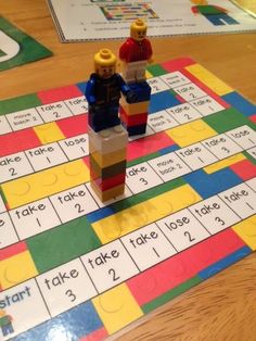 two legos are standing on top of a game board with words and numbers in the middle