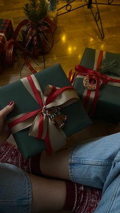 a woman sitting on the floor with two wrapped presents in front of her, both holding hands