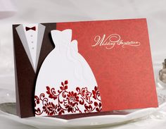 a red and white wedding card with a bride's dress on it, sitting on a plate