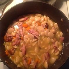 a pot filled with beans and ham on top of a stove