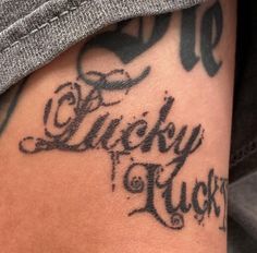 a close up of a person's leg with tattoos on it and the words lucky luck written in cursive writing