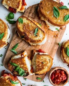 several small sandwiches on wooden cutting boards with sauces and basil sprinkled on them