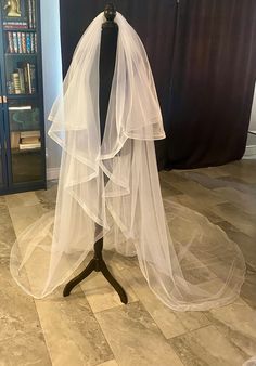 a wedding veil on a mannequin in front of a bookcase