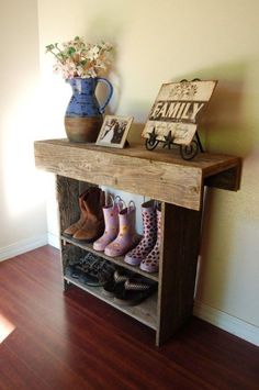 there is a wooden shelf with shoes on it and flowers in a vase next to it