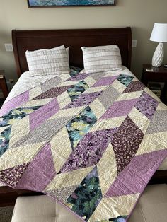 a bed with a purple and white quilt on it