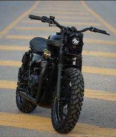 a black motorcycle parked on the side of a road next to a crosswalk with yellow lines