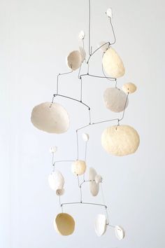 a mobile made out of rocks and pebbles hanging from the ceiling in a room with white walls