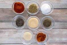 six bowls filled with different types of spices on top of a wooden table next to each other