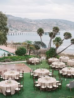 tables and chairs are set up on the lawn for an outdoor wedding reception with palm trees in the background