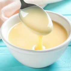 a spoon full of mayonnaise being drizzled into a white bowl