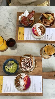 plates and bowls of food sit on wooden trays at a table with menus