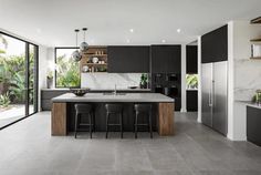 a modern kitchen with black cabinets and marble counter tops is seen from across the room