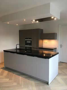 an empty kitchen with black counter tops and stainless steel appliances on the island in front of it