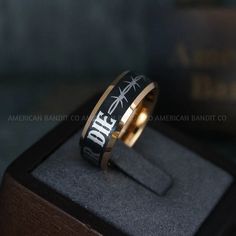 a ring with the words one direction on it in gold and black, sitting inside a wooden box