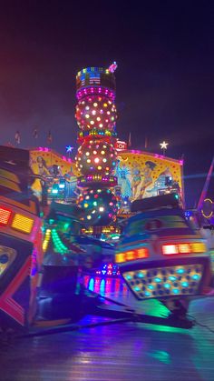 a brightly lit carnival ride at night with lights on the top and bottom part of it