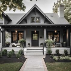 a gray house with white trim and black shutters on the front door, steps leading up to it