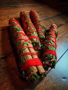 rolled up cinnamons with green and red ribbons on them sitting on a wooden table