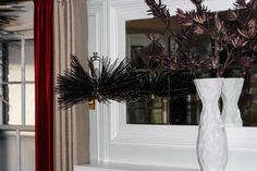 a white vase filled with purple flowers next to a window