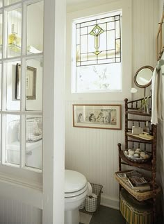 a white toilet sitting next to a window in a bathroom under a stained glass window