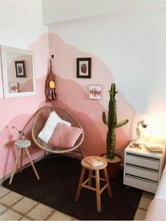 a living room with pink walls and a cactus in the corner next to two stools