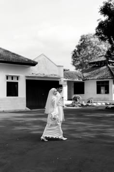 black and white photograph of a bride in front of a house