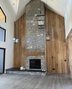 an empty room with a stone fireplace and wood paneling