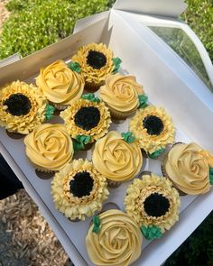 cupcakes with yellow frosting and sunflowers in a box on the grass