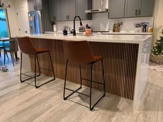 two bar stools sitting in front of a kitchen island