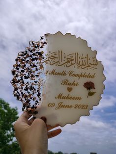 a person holding up a plaque with writing on it in front of a cloudy sky