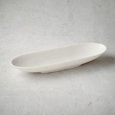 a white oval dish sitting on top of a gray floor next to a black object