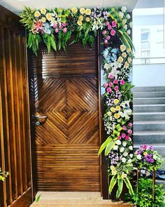 a wooden door decorated with flowers and greenery on the steps leading up to it