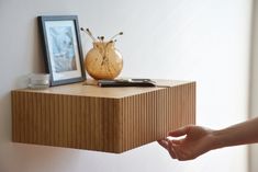 a wooden shelf with a vase on top of it next to a framed photo and other items