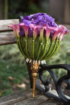 a bouquet of purple flowers sitting on top of a wooden bench