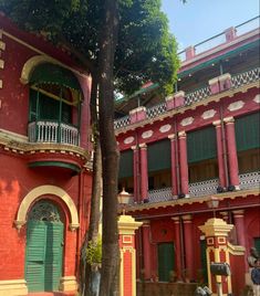 an old red building with green shutters and balconies