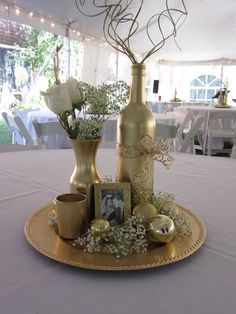 a table topped with two vases filled with flowers and eggs on top of a gold plate