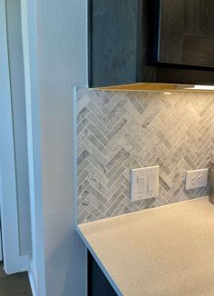 a kitchen counter top with a light switch on it and a white tile backsplash