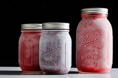 three jars filled with pink and purple liquid