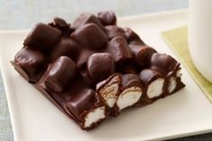 a white plate topped with chocolate and marshmallows next to a cup of coffee