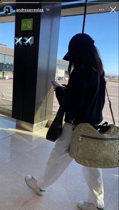 a woman is walking through an airport with her cell phone in her hand and looking out the window