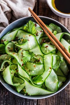 a bowl filled with sliced cucumbers and chopsticks