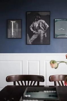 three framed photographs hang on the wall above a dining room table with flowers in it