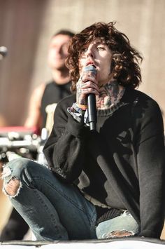 a man sitting on top of a white car while holding a microphone in his mouth