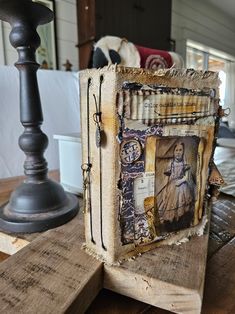 an old book is sitting on top of a wooden table next to a candle holder