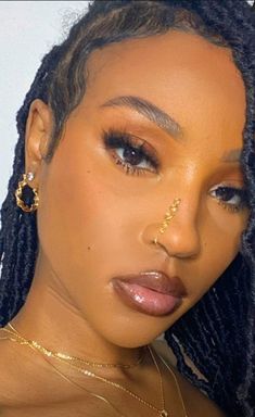 a close up of a person with dreadlocks and gold jewelry on her face